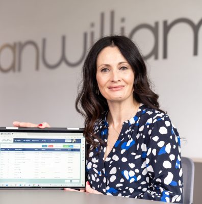 Eileen Byrne, Managing Director Ireland, sits in front of a Lanas sign holding a tablet with the iMedDoc platform on the screen.